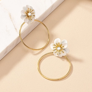 Elegant gold hoop earrings with white matte flower charm and sparkling diamond centers