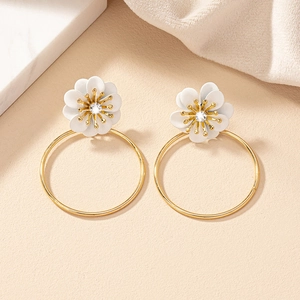 Macro shot of 3D white floral hoop earrings with gold accents and sparkling crystals