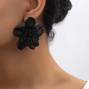 Minimalist matte black floral stud earrings with layered petals on female model
