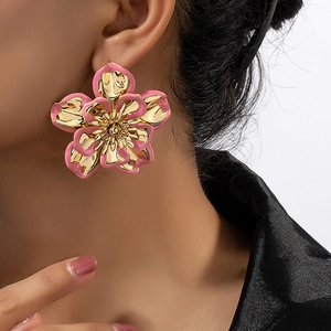 Close-up of elegant gold and pink enamel flower earring worn as a fashion accessory