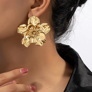 Close-up of elegant gold flower earrings with detailed petals worn by a model