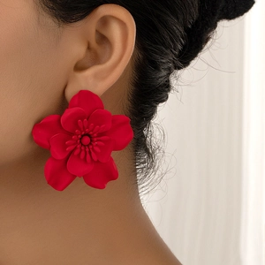 Close-up of matte red flower earrings worn by a model showcasing floral details