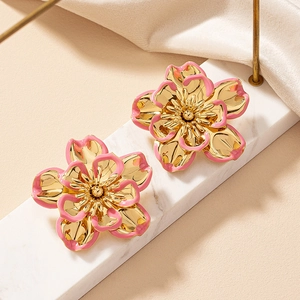 Retro golden flower earrings with pink enamel petals on a luxury marble surface