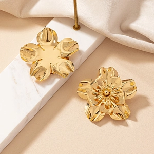 Macro detail of asymmetric golden flower earrings with polished metallic petal finish