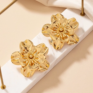 Macro shot of 3D layered gold flower earrings with metallic mirror finish and stamens