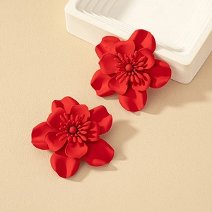 Detailed close-up of large red floral earrings with matte finish and 3D petal structure