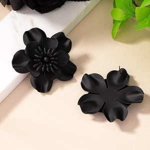 Detailed macro view of matte black layered flower earrings with needle structure and petals