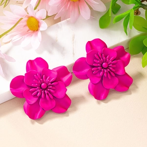 Detail of rose red 3D flower earrings with matte layered petals on marble display