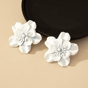 Detailed close-up of white 3D flower earrings with layered petals and matte finish