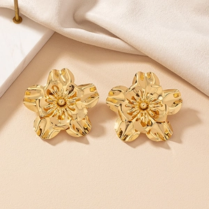 Macro detail of elegant golden flower stud earrings with layered metallic petals