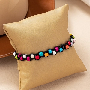 Detailed close-up of colorful beads on a woven Bohemian rope bracelet displayed on a pillow