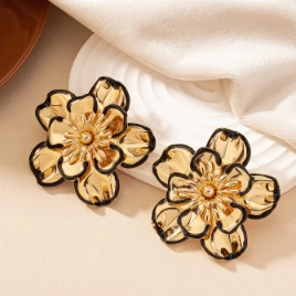 Close-up of golden vintage flower earrings with layered petals and black enamel edges