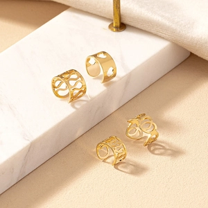 Gold heart and wave hollow cuff earring set on a white marble background surface
