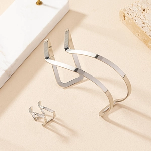 Close-up of polished silver geometric wave bracelet and matching ring on stone