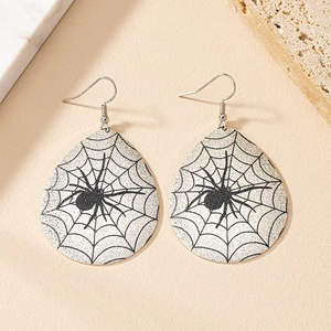 Detail view of teardrop earrings with spider web pattern on textured background