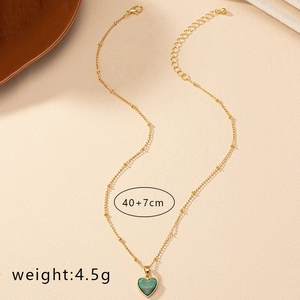 Detail of a 40+7cm gold heart necklace featuring a green malachite pendant and beaded chain