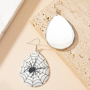 Detail view of teardrop earrings with black spider web pattern on stone pedestal