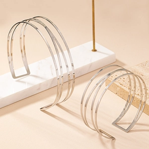 Dettaglio di bracciali a polsino geometrici argento su elegante sfondo di marmo