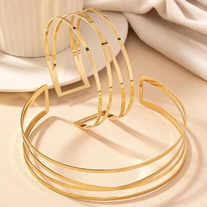 Dettaglio di un set di due bracciali rigidi dorati aperti con design geometrico lucido