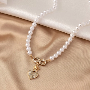 Luxe parelketting met gouden oneindigheidskroon hanger en sprankelende strass-steentjes