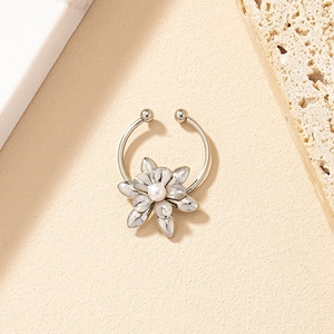 Detalle macro de un brazalete de nariz floral plateado con perla blanca y diseño abierto