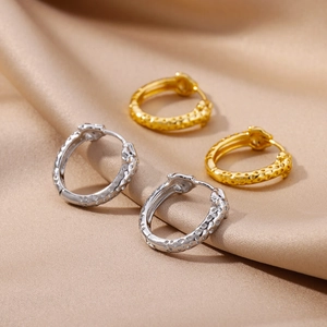 Detail of 18k gold and silver hammered hoop earrings on elegant silk background