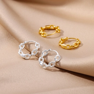Detail of 18k gold plated chain link earrings with zircon on champagne silk background