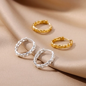 Close-up of 18k gold and silver plated chain-link earrings on champagne silk fabric