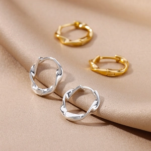 Detailed view of gold and silver twisted hoop earrings on champagne silk fabric