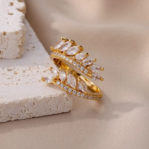 Close-up of golden crown ring with marquise-cut zircons on textured stone and silk