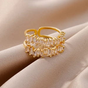 Close-up of golden double-layer open ring with baguette-cut zircons on silk fabric