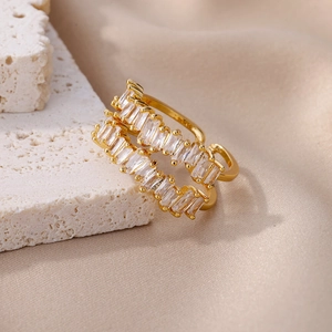 Detailed macro shot of golden double-row baguette-cut zircon rings on beige silk fabric