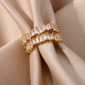 Detail of 18K gold double-row ring with baguette-cut zircon on champagne silk fabric