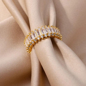 Macro shot of gold eternity ring with rectangular white zircons on champagne satin