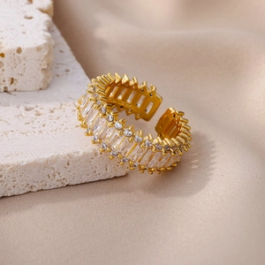 Close-up of gold open ring with rectangular and round cubic zirconia in prong setting