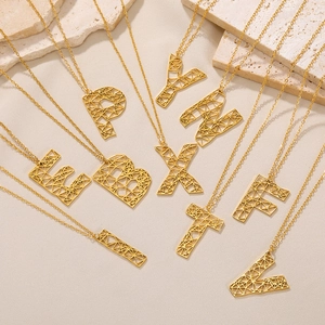 Detail van gouden geometrische letterhangers aan verfijnde ronde O-kettingen