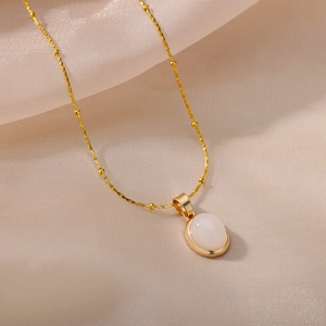 Detail of elegant gold bead chain with oval white cat eye stone pendant on silk fabric
