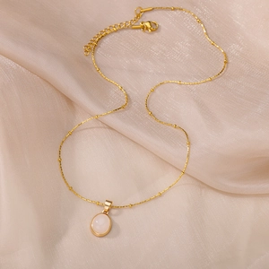 Detail of elegant gold titanium necklace with oval cat-eye pendant on silk fabric