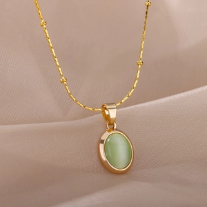 Detail of a gold satellite chain necklace featuring an oval green cat-eye stone pendant