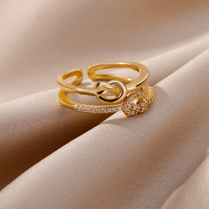 Detail of gold double-layer knot ring with white zircon stones on champagne silk