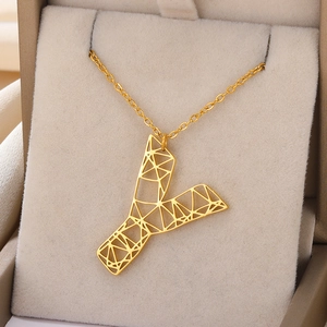 Detail van de gouden holle Y-letter hanger met geometrische patronen op beige kussen