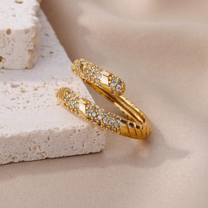 Detail of gold spiral ring with pavé-set zircons on textured stone display