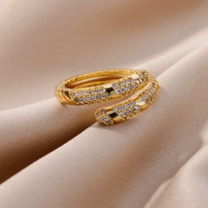 Macro detail of gold-plated geometric ring featuring layered cubic zirconia cross band