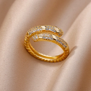 Detailed close-up of golden spiral ring with zircon stones on champagne silk