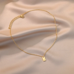 Minimalist gold stainless steel necklace with rectangular initial A pendant on satin