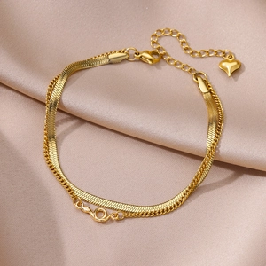 Close-up of golden double-layer herringbone and link chain anklet on champagne silk