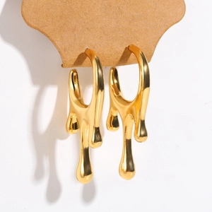 Macro shot of gold liquid lava metal drop earrings on a brown display card