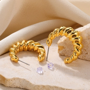 Macro shot of gold croissant hoop earrings on stone platform with silk texture