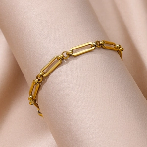 Close-up of gold paperclip link chain bracelet on soft pink silk background