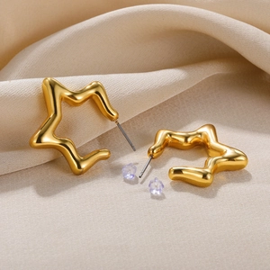 Macro shot of gold star stud earrings with wavy edges on a luxury silk background